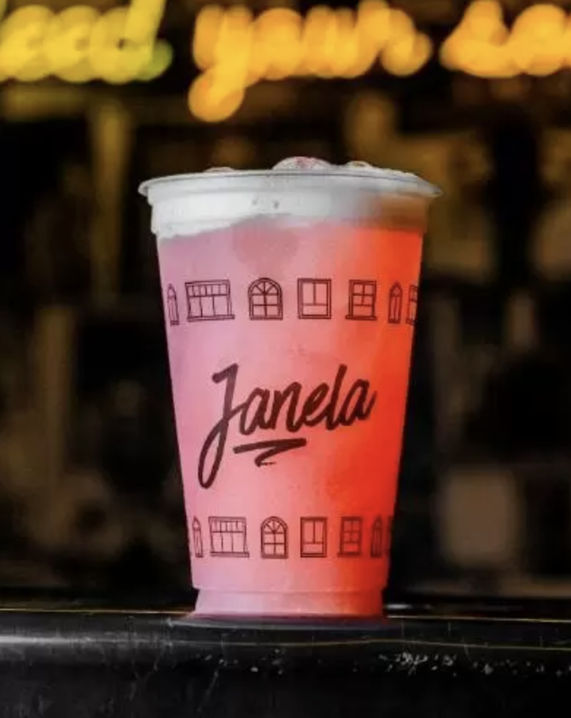 Drink autoral rosa servido em copo com a marca Janela