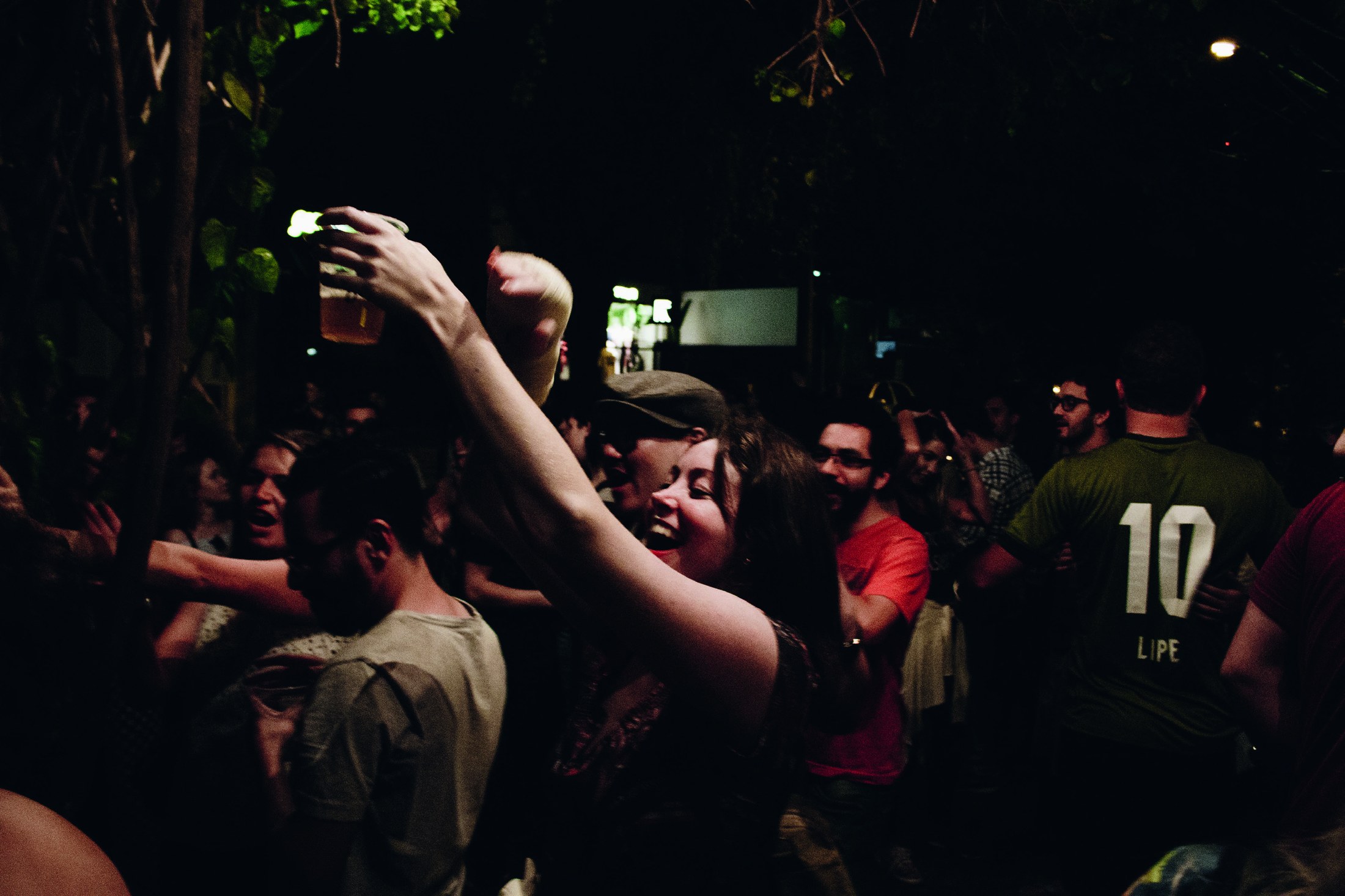Galera cantando junto com as mãos para o alto dentro do bar